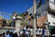 Un padre entrega a su hija para que la pasen por encima de la valla de la oficina de inmigración de Haití mientras esperan su turno para solicitar un pasaporte, en Puerto Príncipe, Haití, el jueves 9 de febrero de 2023.