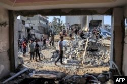 La gente se reúne junto a los escombros de un edificio después de un ataque aéreo israelí en Rafah, en el sur de la Franja de Gaza, el 13 de octubre de 2023.