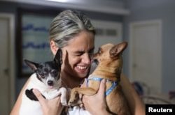 Karolina Vásquez Ramírez con sus perros Bingo y Dasha en su casa antes de partir hacia el aeropuerto, en La Habana, Cuba, el 25 de octubre de 2023. REUTERS/Carlos Carrillo