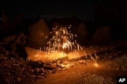 Un niño palestino juega con fuegos artificiales mientras celebra el inicio del mes sagrado musulmán del Ramadán junto a una mezquita destruida por los ataques aéreos israelíes en Rafah, Franja de Gaza, el domingo 10 de marzo de 2024. (Foto AP/Fatima Shbair)