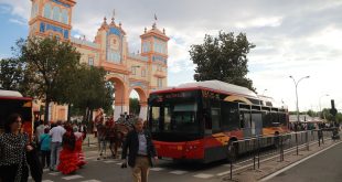 Un autobús de Tussam pasando junto a la Portada de la Feria de una edición anterior.