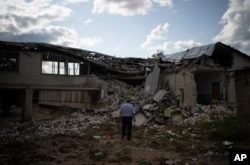 Oleksandr Pishchyk, frente a la biblioteca de la escuela que dirigía antes de ser destruida por los bombardeos en Kupiansk, Ucrania, el miércoles 23 de agosto de 2023. (Foto AP/Bram Janssen)