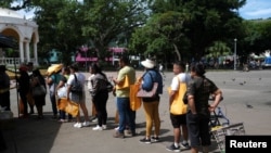 La gente hace cola para comprar verduras en un mercado establecido por el gobierno como parte de un plan para revertir el aumento de los precios de los alimentos en Santa Tecla, El Salvador.