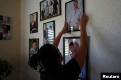 Belkis Martínez cuelga una fotografía de su hijo, que desapareció en una embarcación en algún lugar entre Cuba y el sur de Florida, Palma Sola, Cuba, 19 de junio de 2024. REUTERS/Alexandre Meneghini