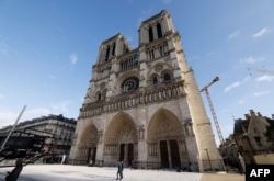 La gente camina frente a la catedral de Notre-Dame de París, antes de su ceremonia de reapertura oficial después de más de cinco años de trabajos de reconstrucción tras el incendio de abril de 2019, en París el 7 de diciembre de 2024.