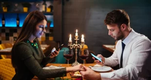 Una pareja en plena cena, cada uno con el teléfono en la mano.