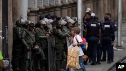 Un vendedor ambulante camina junto a miembros de la Guardia Nacional Bolivariana antes de la juramentación del presidente Nicolás Maduro para un tercer mandato, en Caracas, Venezuela, el domingo 5 de enero de 2025.