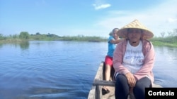 Mujeres navegan por una ciénaga para ver en qué punto pueden tirar su atarraya, en la localidad de Cerrito, en el Caribe colombiano, diciembre de 2024.