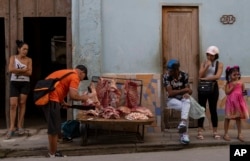 A seller of short pork pieces for buyers waiting for their turn on the sidewalk of Havana, Cuba, on February 14, 2025. (PHOTO AP/RAMON ESPINOSA)