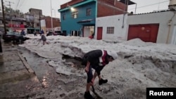 La gente quita el hielo grueso de una calle después de una tormenta de granizo en medio de una ola de calor, en Puebla, México, el 24 de mayo de 2024.