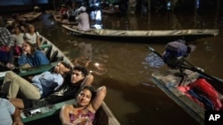 Los espectadores ven desde barcos una película proyectada en una pantalla instalada sobre una estructura de madera durante el Festival de Cine Flotante Muyuna, que celebra los bosques tropicales, en el barrio Belén de Iquitos, Perú, el 25 de mayo de 2024.