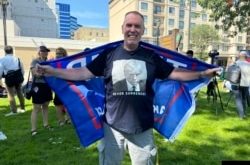 Un seguidor del Donald Trump viste una camiseta con la foto policial del expresidente durante una vigilia en la ciudad de Milwaukee para rezar por la salud y seguridad del candidato presidencial republicano, víctima de un atentado el día anterior en un mitin de campaña.