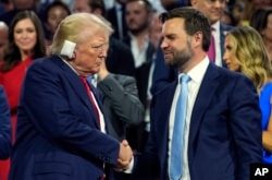 El candidato presidencial republicano, el ex presidente Donald Trump, y el candidato republicano a la vicepresidencia, el senador por Ohio JD Vance, asisten al primer día de la Convención Nacional Republicana, el lunes 15 de julio de 2024, en Milwaukee. (Foto AP/Evan Vucci)