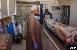 Un trabajador palestino se encuentra en una morgue cerca de un cadáver en un hospital tras un bombardeo israelí, el 7 de septiembre de 2024, en Deir el-Balah, en el centro de la Franja de Gaza. (Foto de Eyad BABA / AFP)