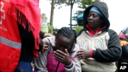 El personal de la Cruz Roja de Kenia y sus familiares intentan consolar a una mujer que reacciona cerca de un dormitorio quemado, luego de un incendio en la escuela primaria Hillside Endarasha en Nyeri, Kenia, el viernes 6 de septiembre de 2024.