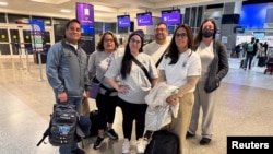 Ana María Haefmeyer, 36, and Adamary 'Ada' García, 40, pose for a photo with other people before boarding a flight to Chile, where they will meet with their biological family, at the George Bush intercontinental airport in Houston in Houston , Texas, on February 21.